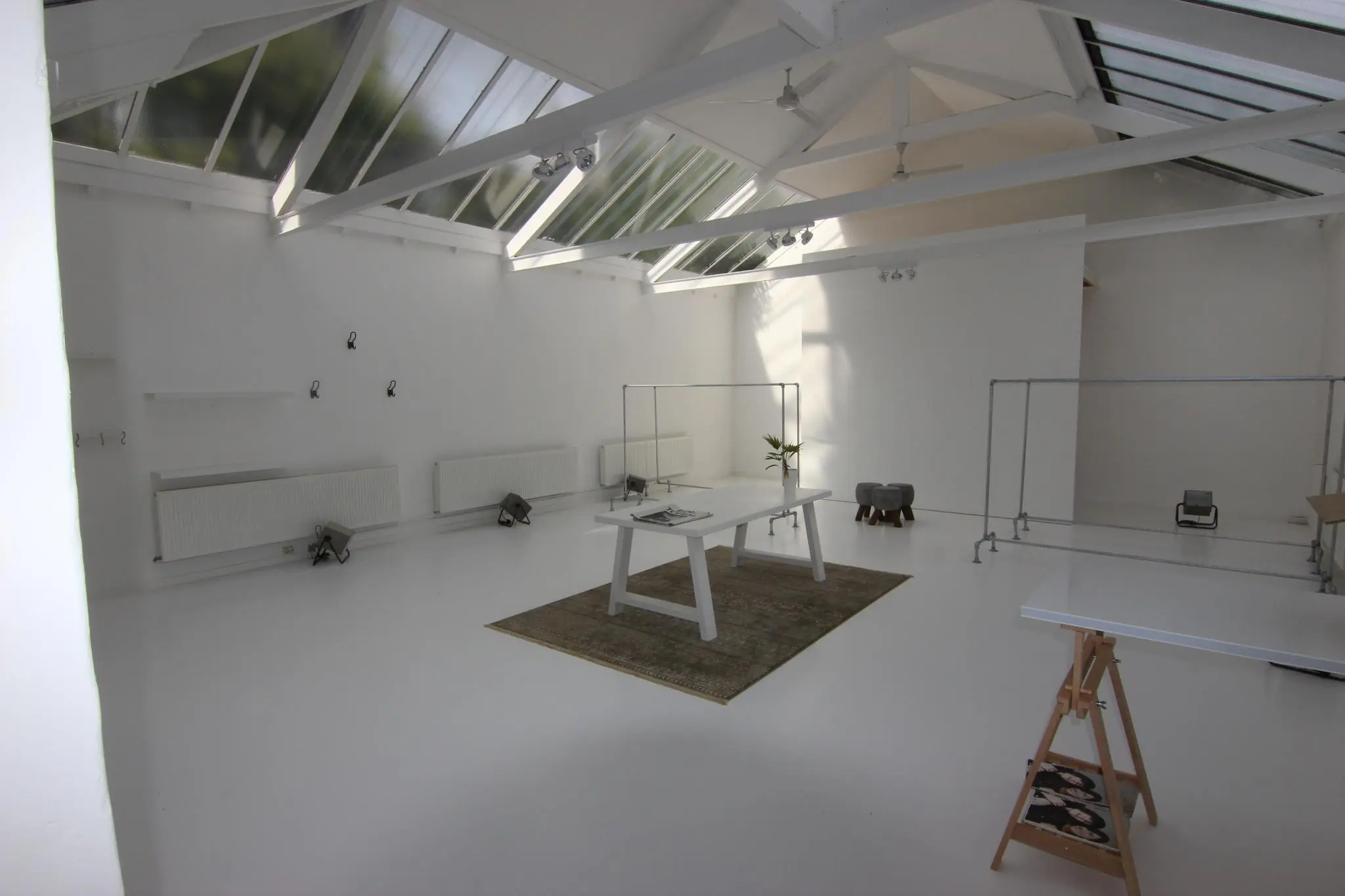 Licht en minimalistisch ingericht atelier met witte muren, grote dakramen en een werktafel op een vloerkleed aan de Graaf Florisstraat.